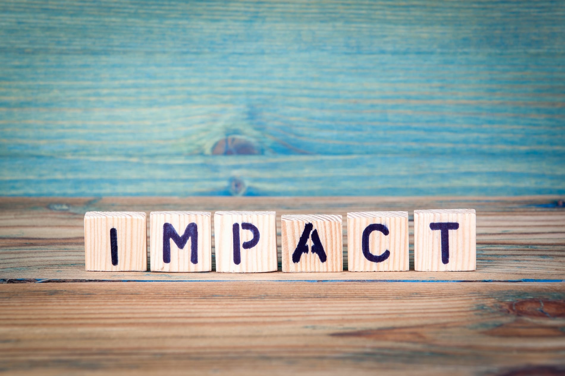 The word 'impact' spelt out on wooden tiles