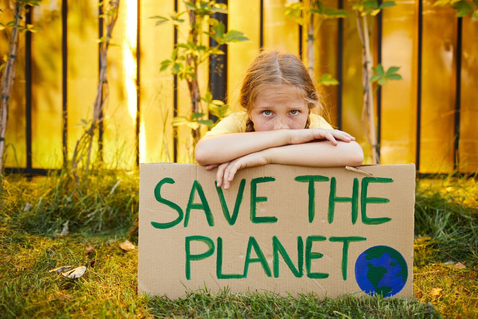 Portrait of teenage girl holding SAVE THE PLANET sign and looking at camera