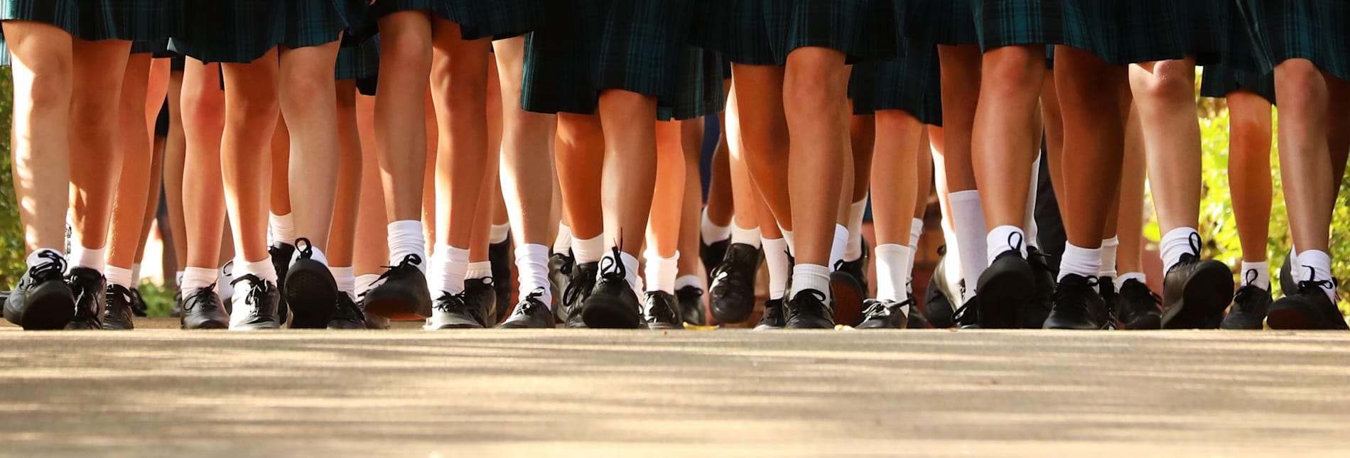 The legs of a group of uniformed schoolgirls walking together