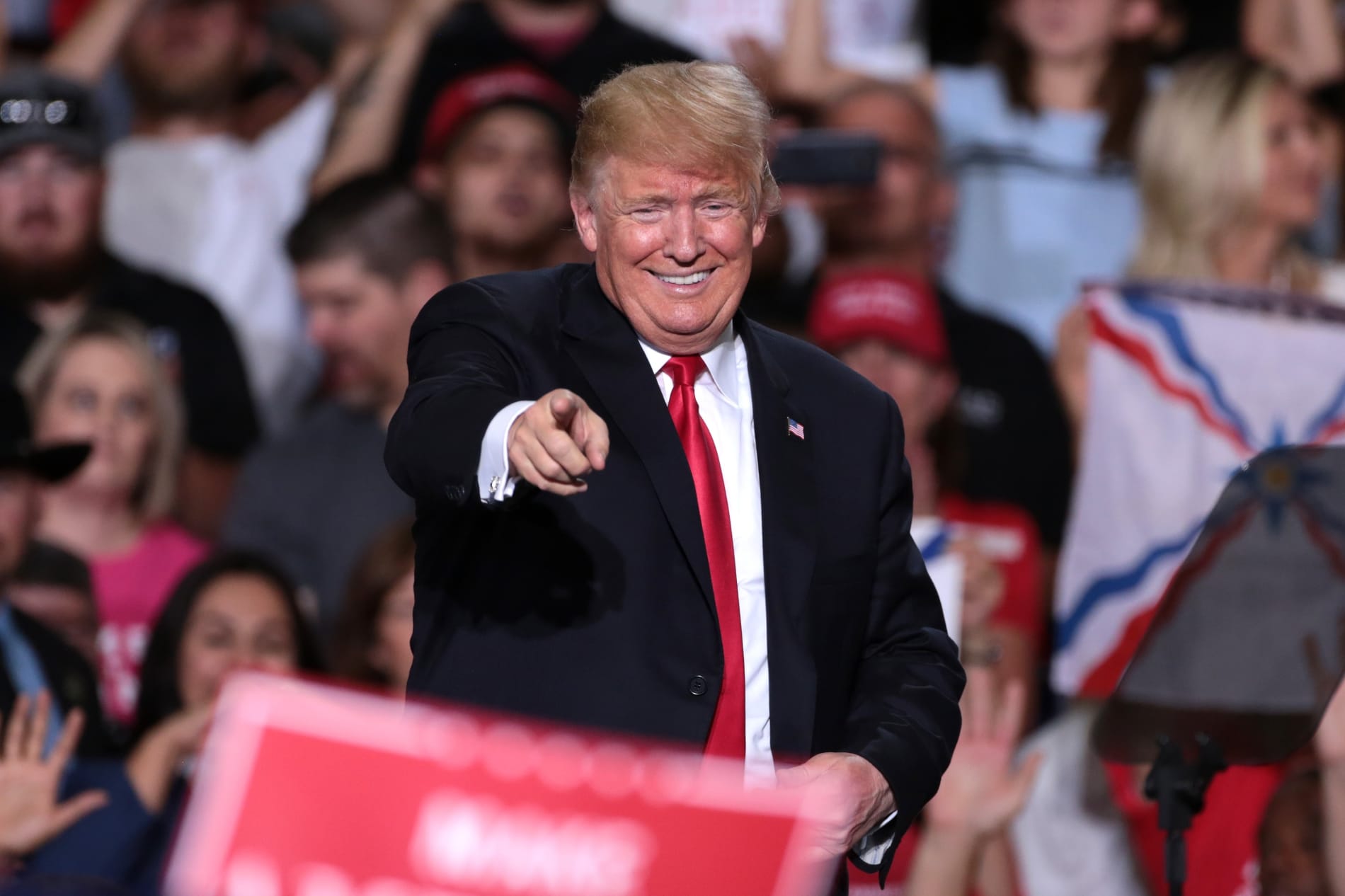 A smiling and pointing Donald Trump at a campaign rally.