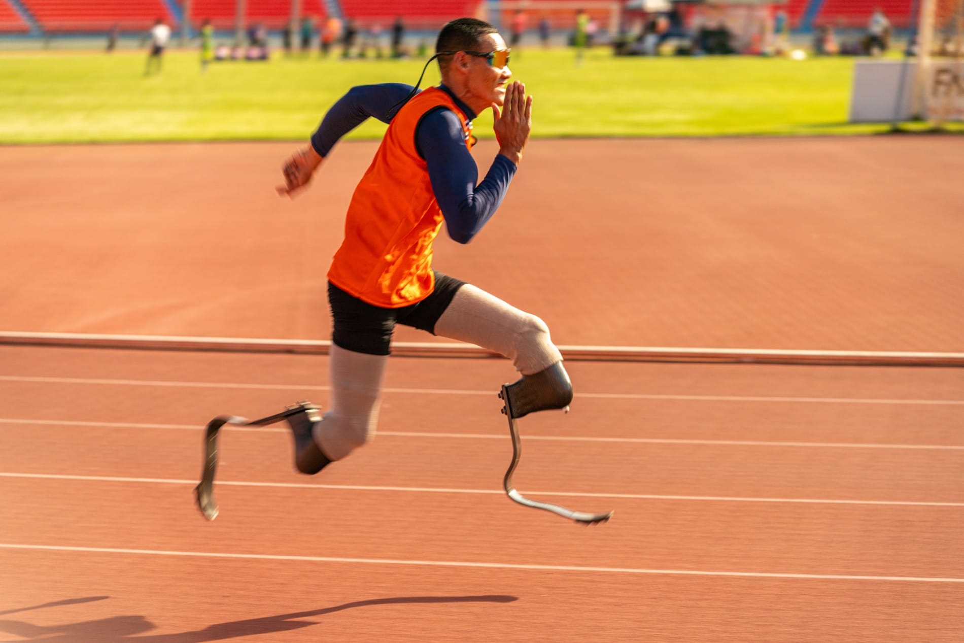 A para-athlet with prosthetic blade legs sprinting on an athletics track