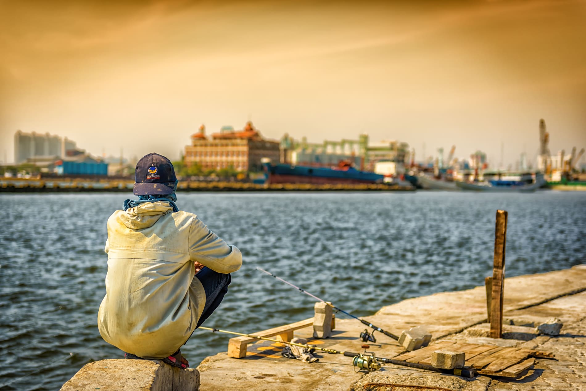 Indonesian boy sits by water.