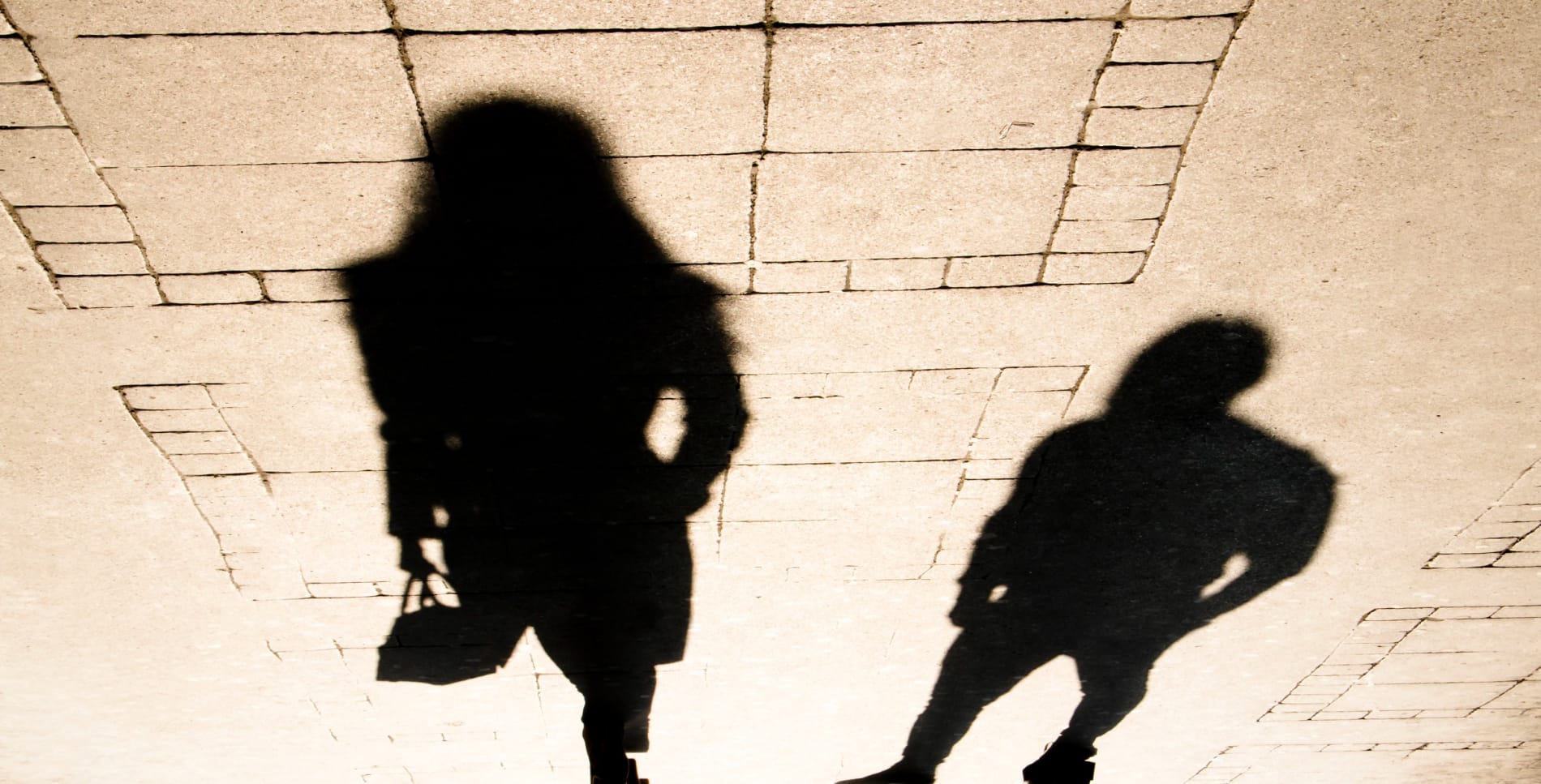 Silhouette shadow of a woman and a man on city sidewalk in sepia black and white