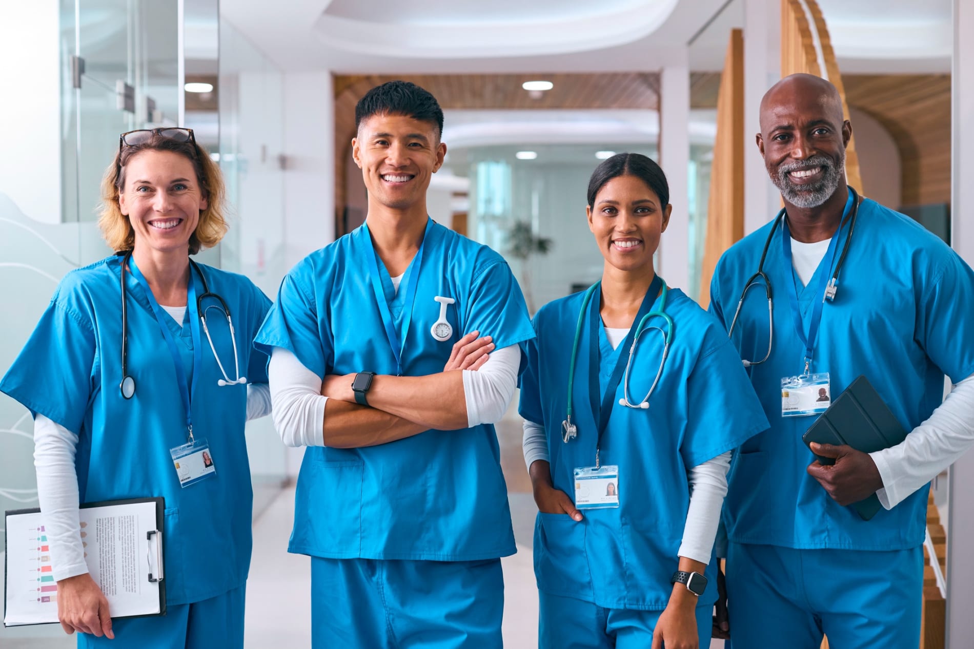 Portrait Of Smiling Multi Cultural Medical Team Wearing Scrubs In Modern Hospital