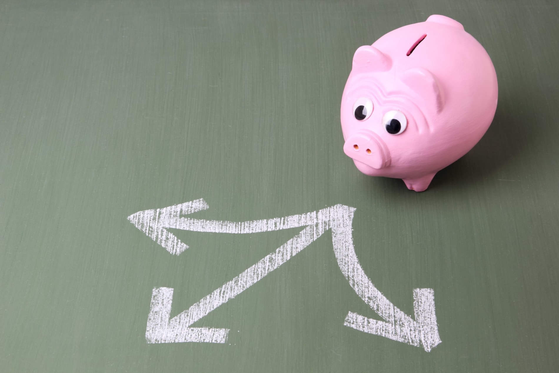 A pink piggy bank with arrows in chalk pointing in three directions