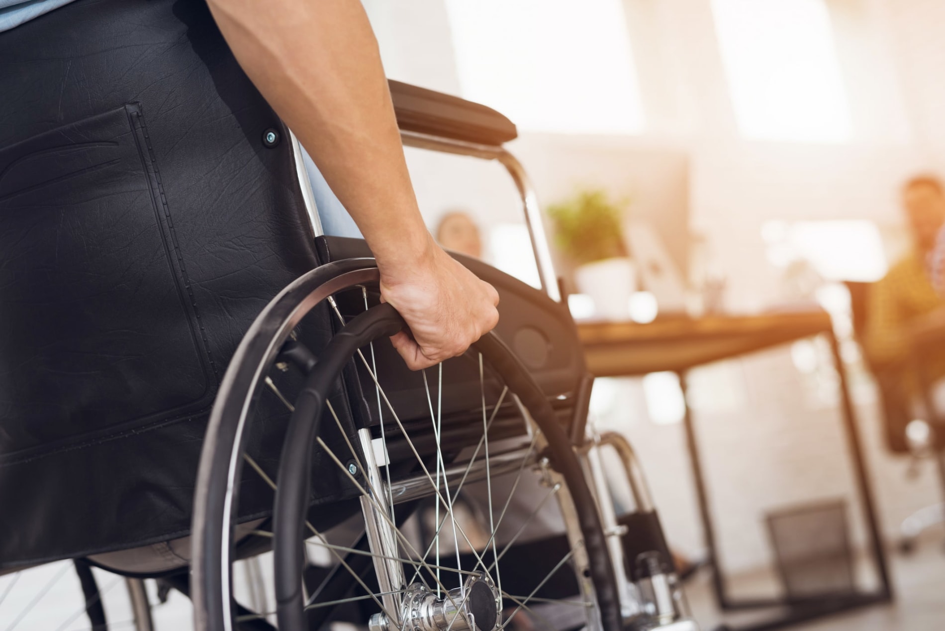 A young man in a wheelchair, with his hand on the wheel