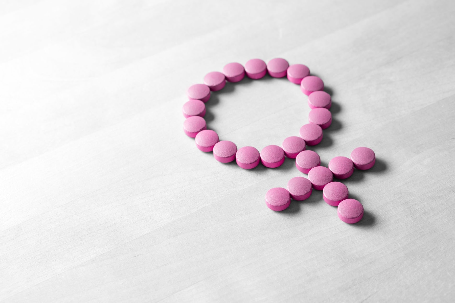 Female gender symbol made from pink pills on a table