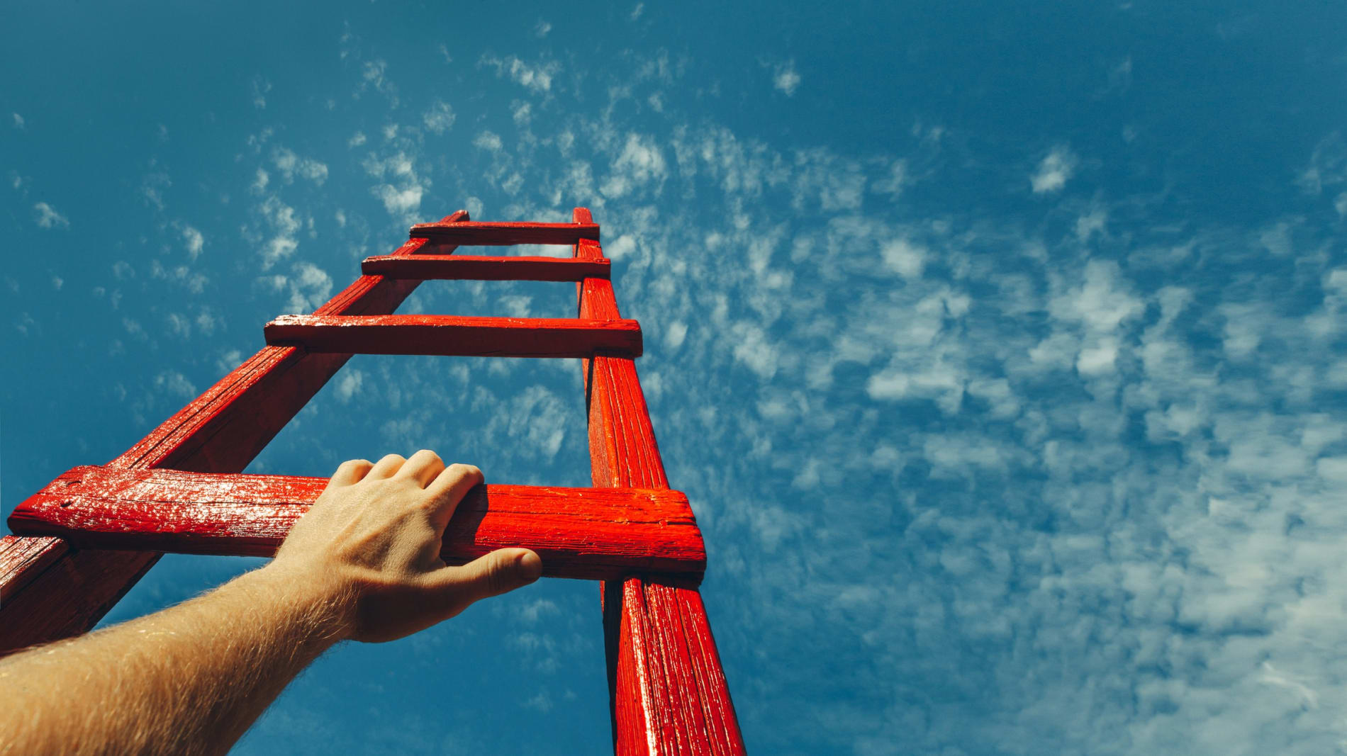 Low angle view of young businessman moving to the top of ladder.