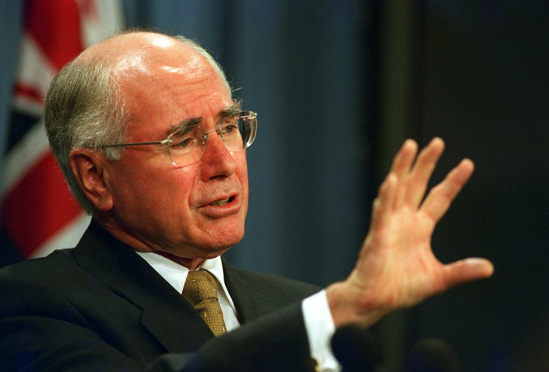 Former Australian prime minister John Howard speaks with hand outstretched