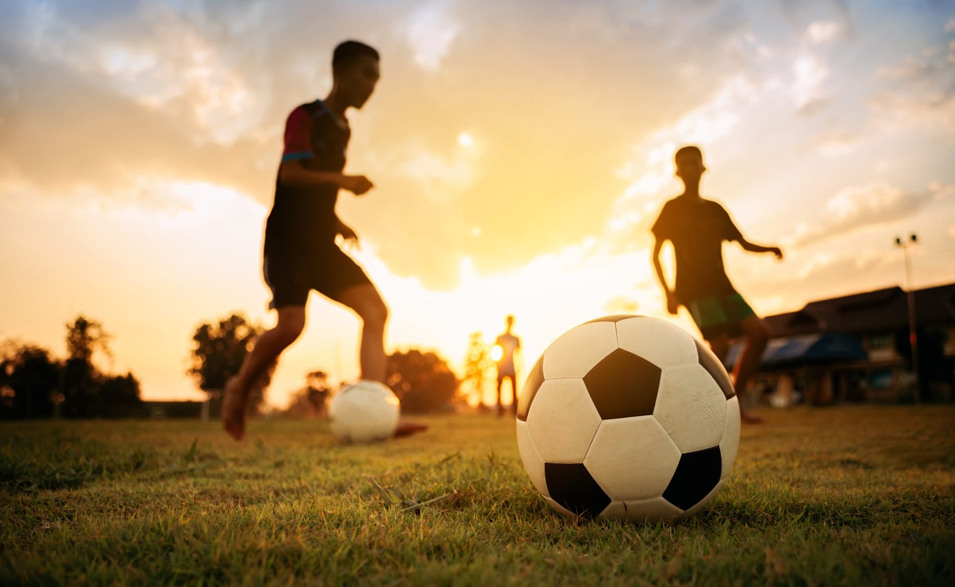 Silhouetted group of kids playing soccer under the twilight sunset sky