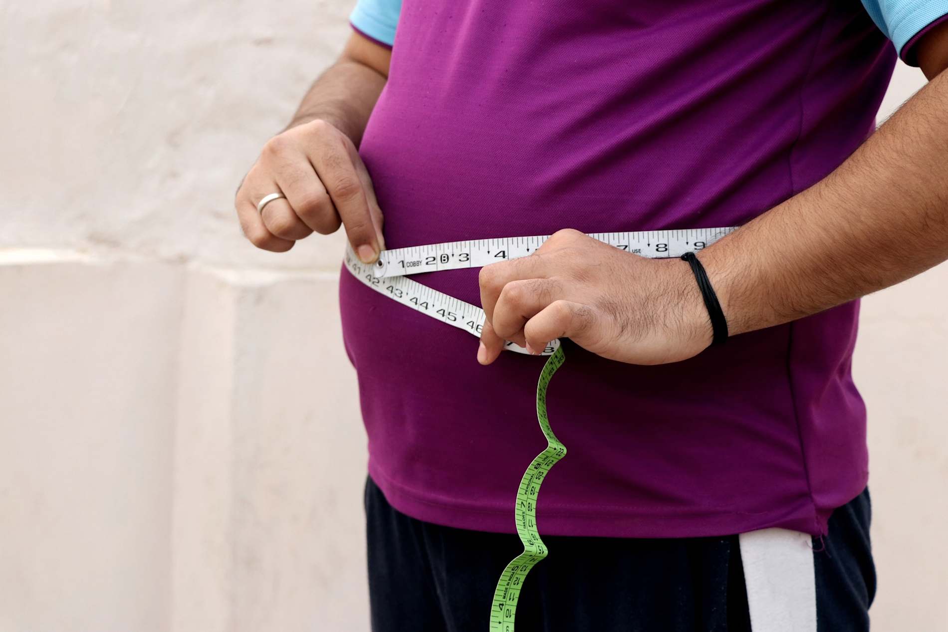 A man measuring his waist with a measuring tape.