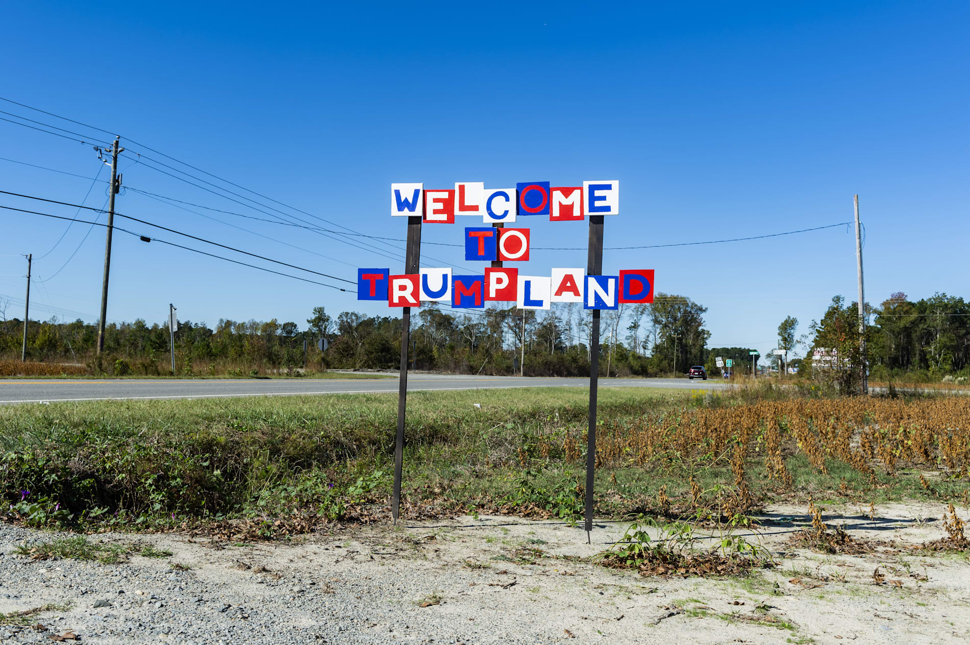 A roadside sign in red, white and blue reading "Welcome to Trumpland"