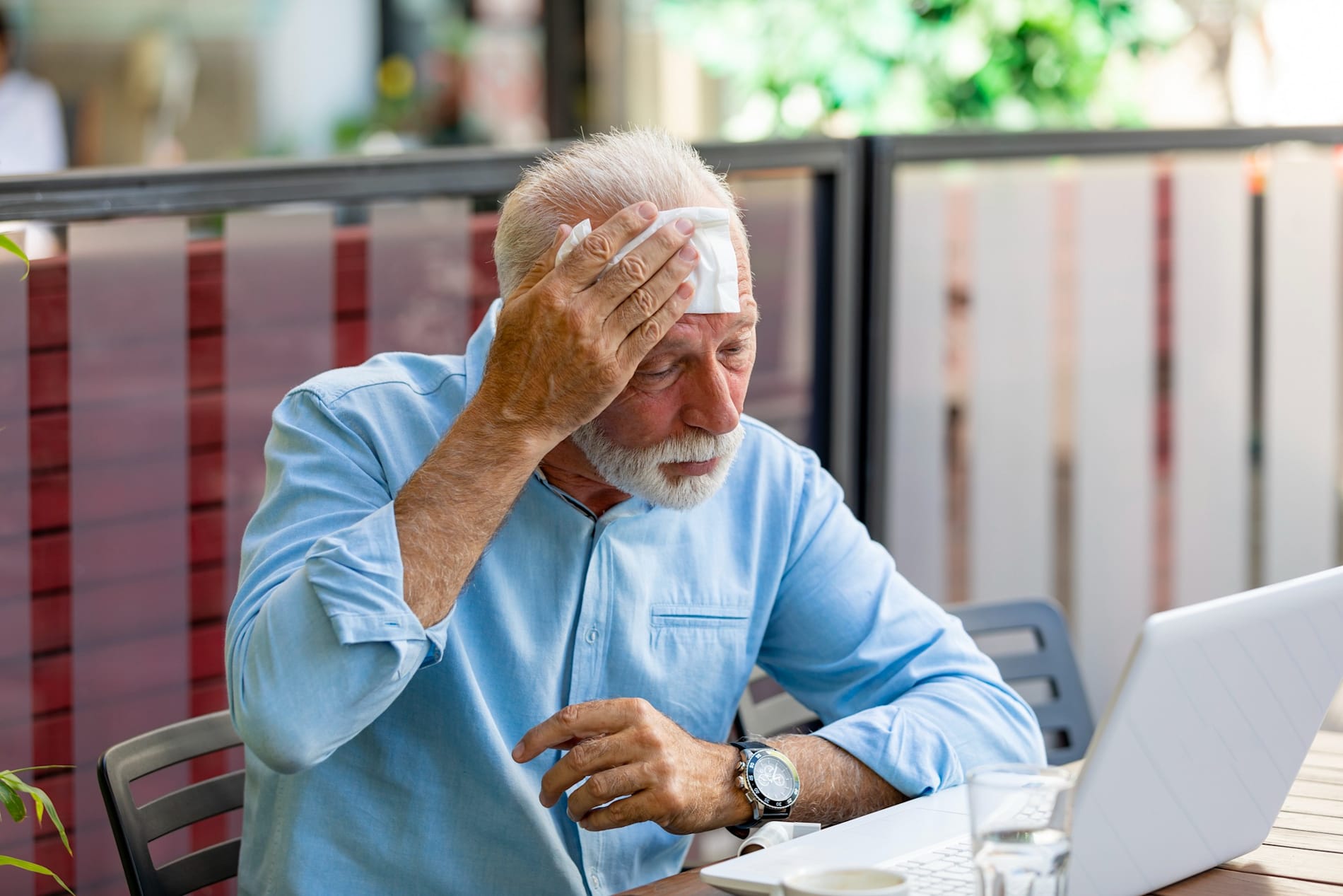 Older person suffering from heat, wipes his brow.