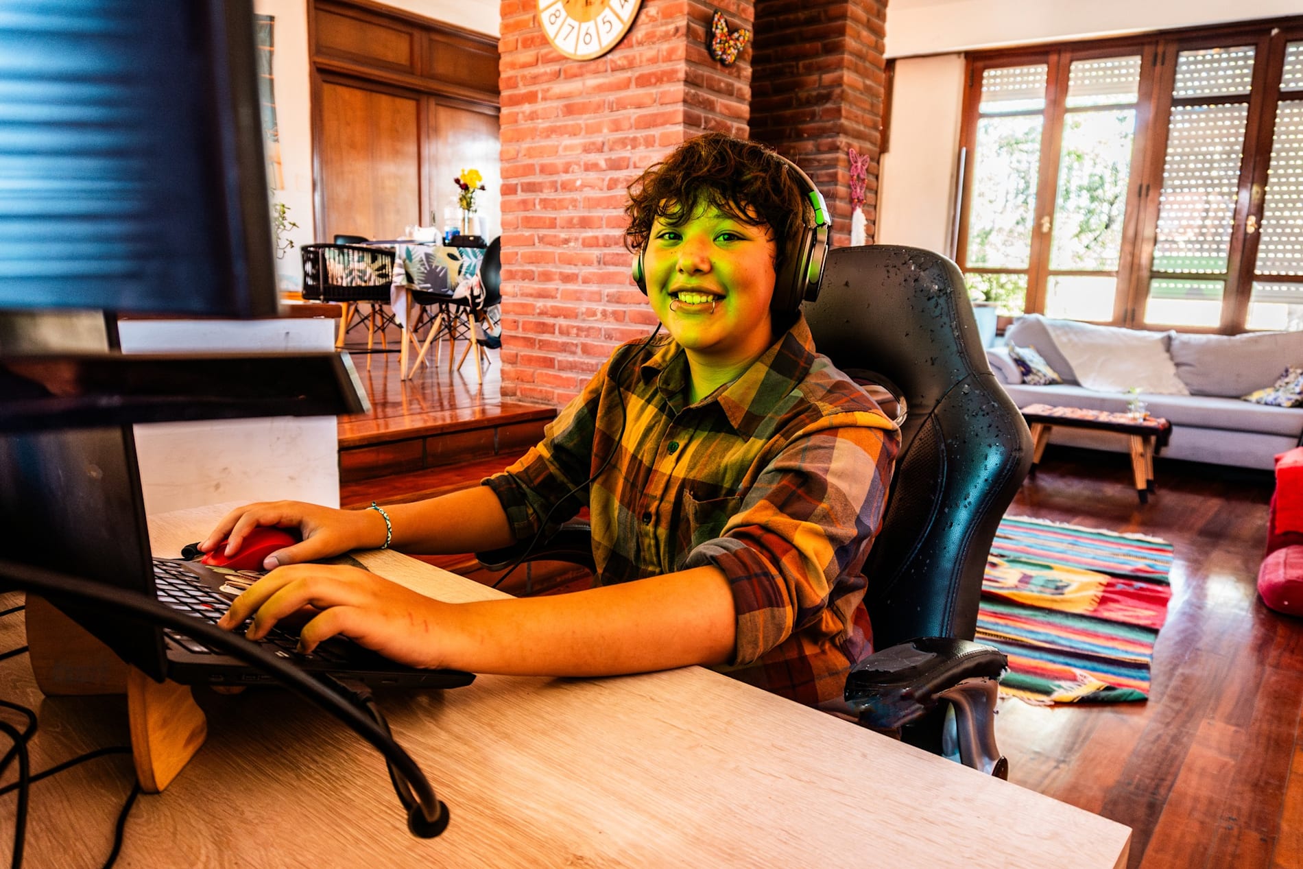 Portrait of a happy transgender person sitting at a computer playing video games.