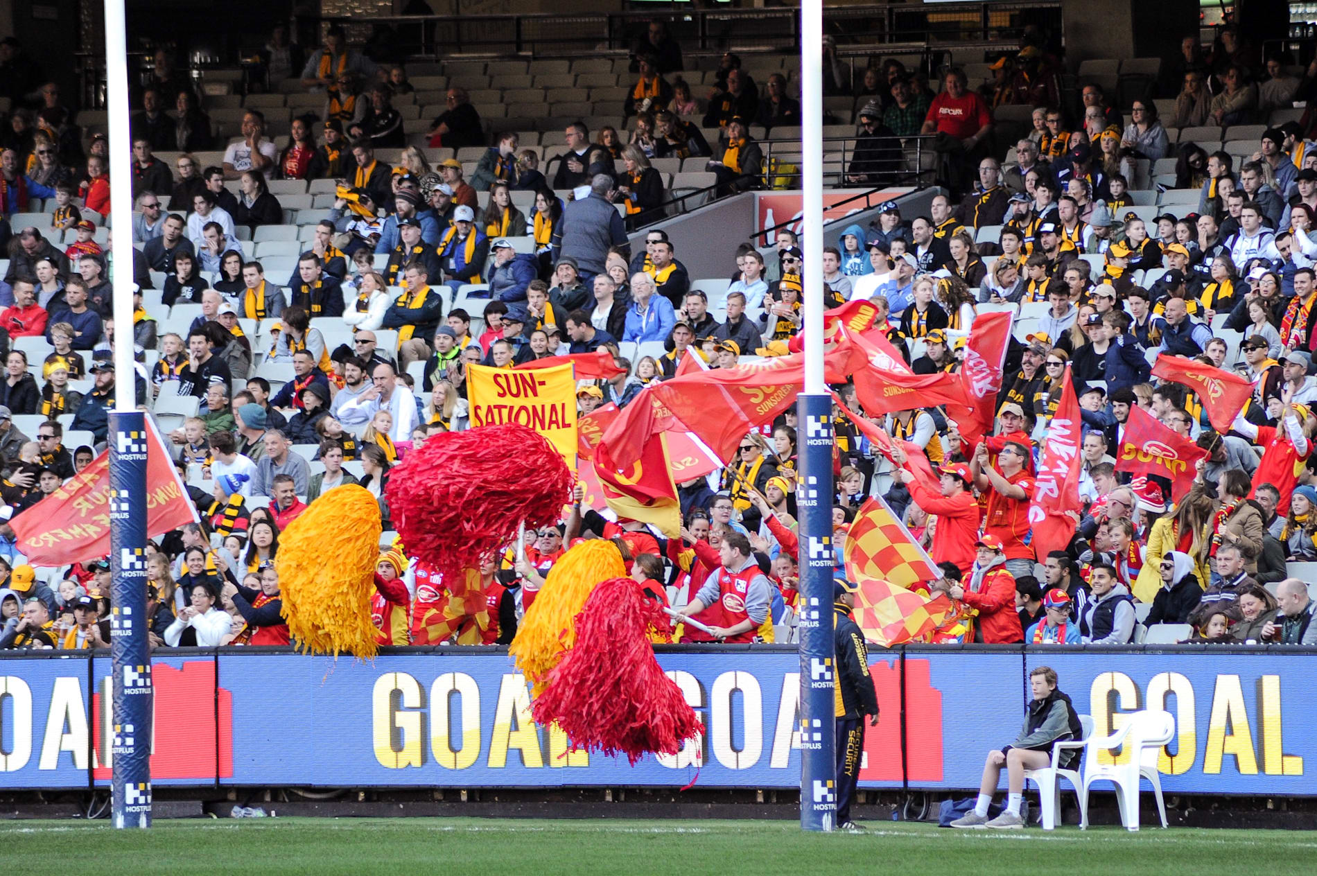 Gold Coast Suns cheer squad wave flags in a crowd