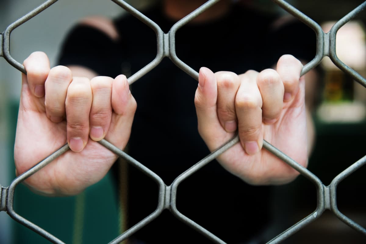 White woman's hands on prison fence