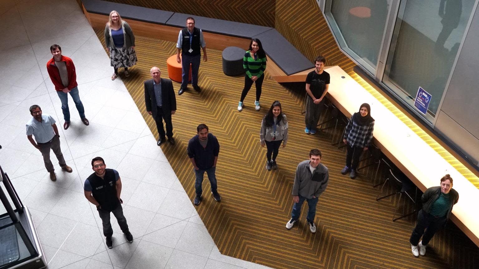 Group shot taken from above of the PhD students, in casual attire, who worked on the COVID blood test project.