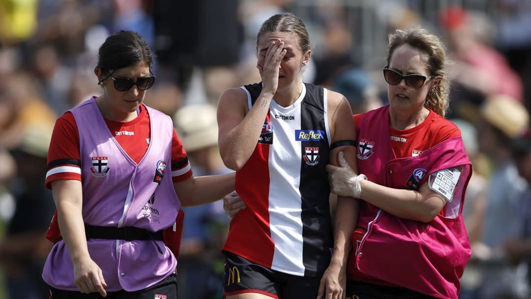 Pic of St Kilda AFLW player being helped from the field by two team medical staff after head injury