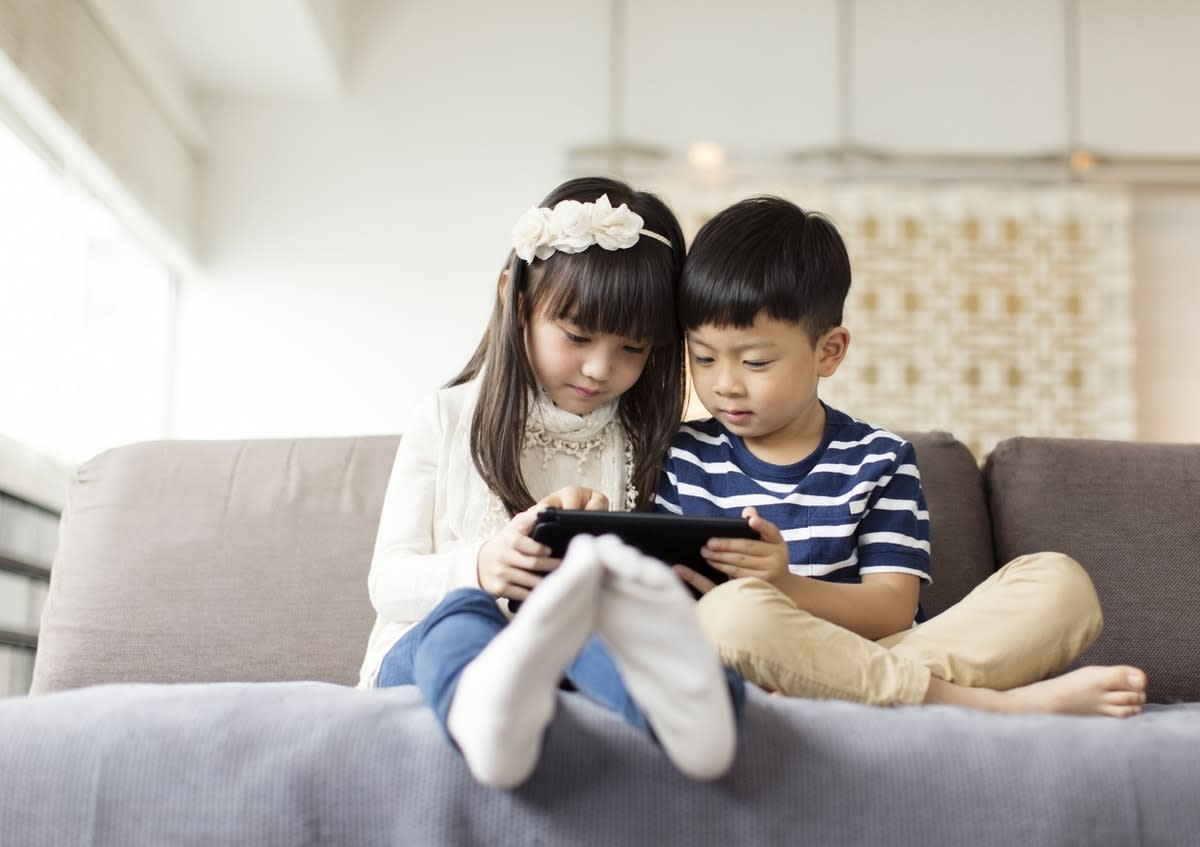 Image of a small boy and girl on a couch looking at an iPad