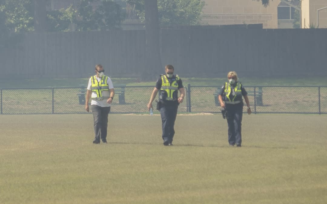 Police wearing protective masks patrol a park.