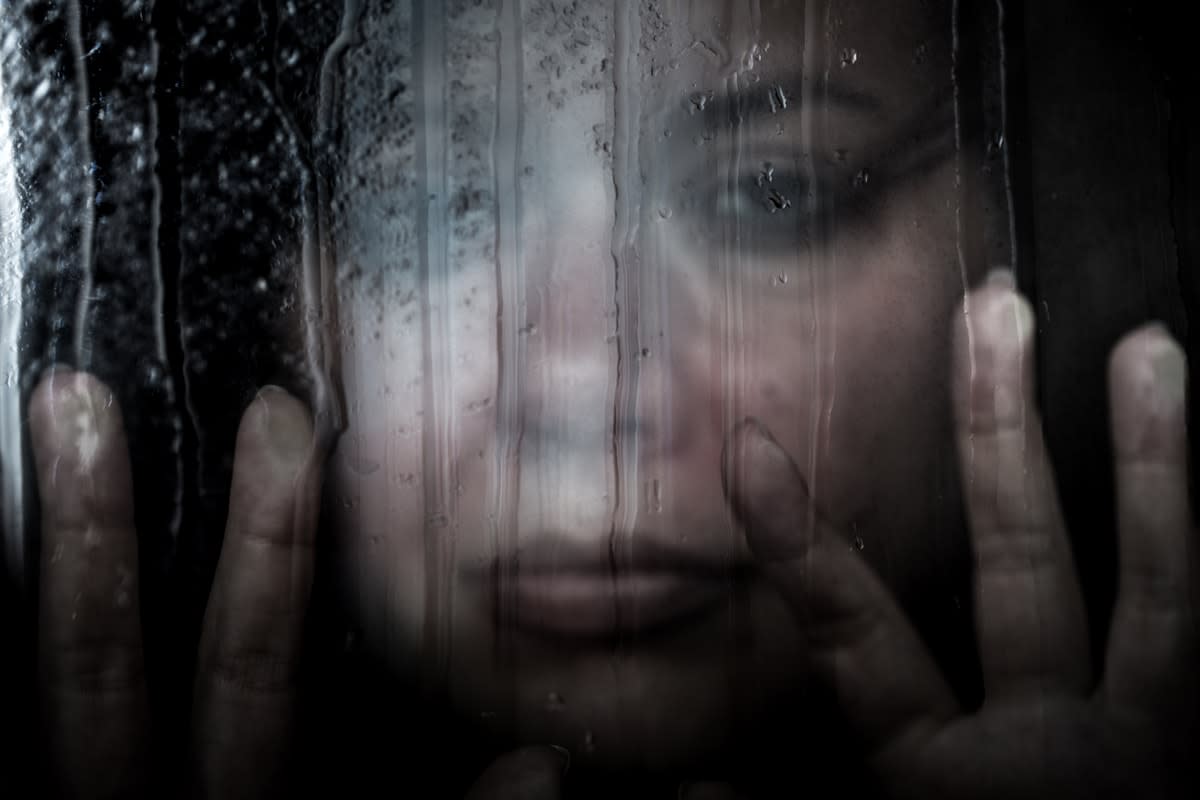 Depressed woman staring out a rain-soaked window 