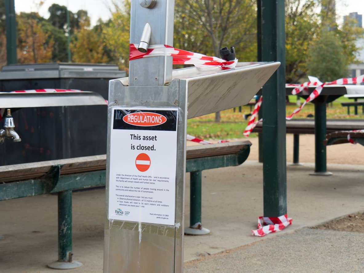 A taped-off public park seating area with a sign reading ‘Restrictions: this asset is closed‘ 