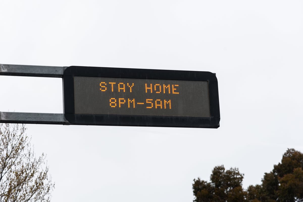 An overhead road sign in Melbourne reading "Stay home 8pm-5am"