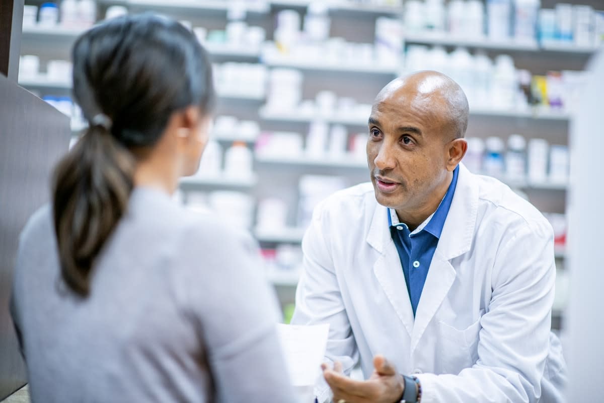 A male pharmacist talking to a female customer