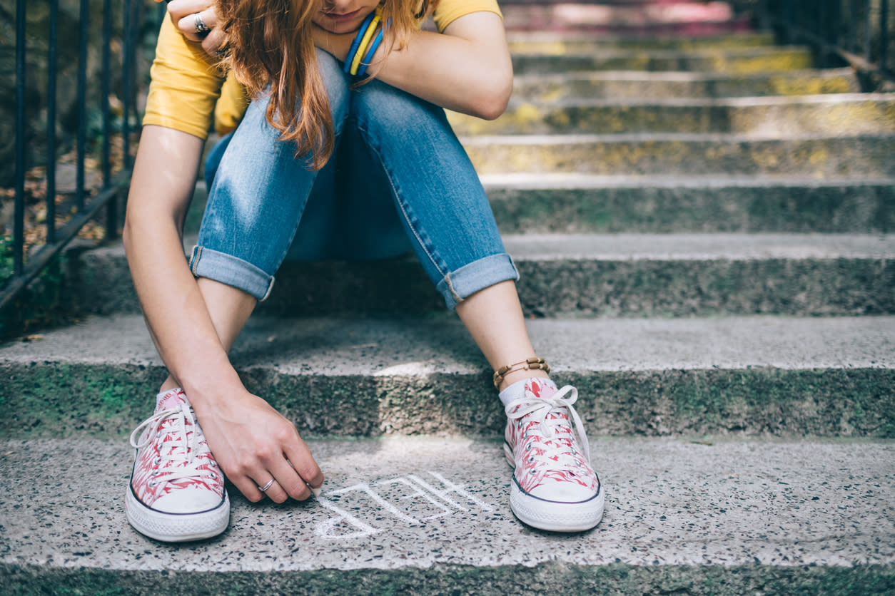 Girl sitting on steps writing ‘HELP‘