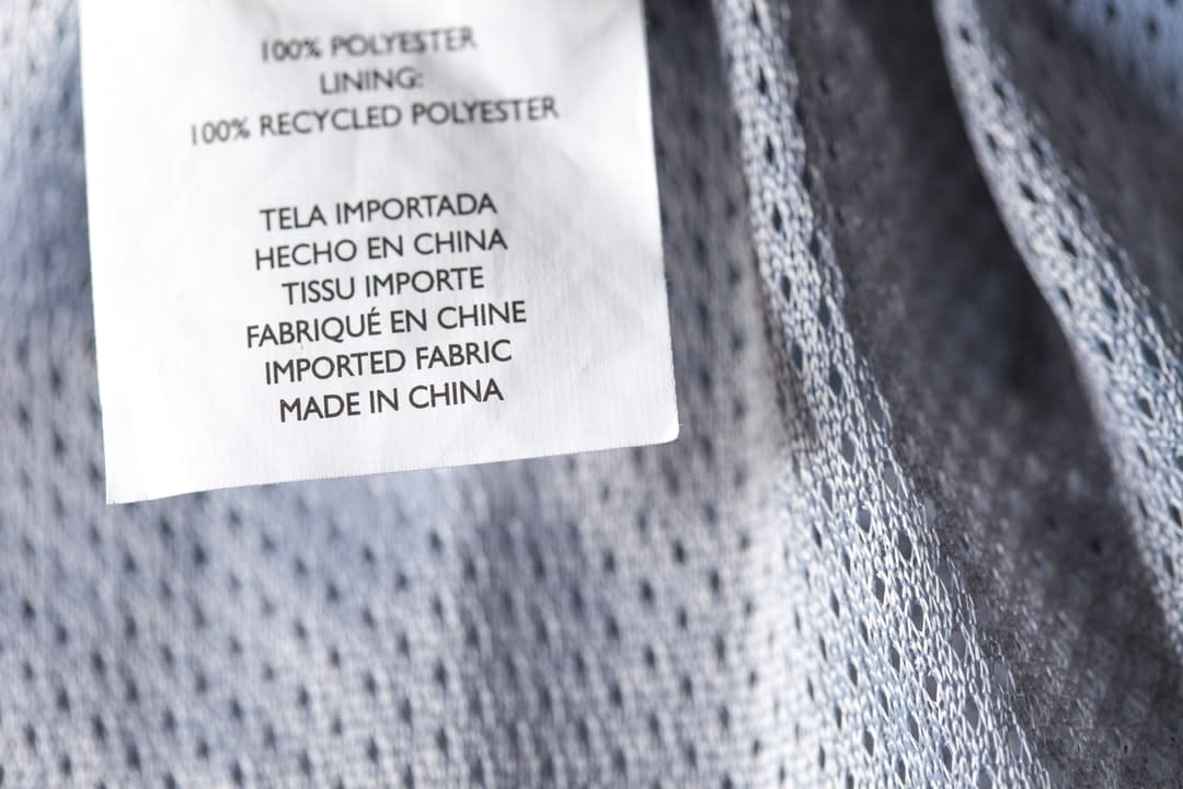 A textile garment with a tag stating it was made from 100% recycled polyester.