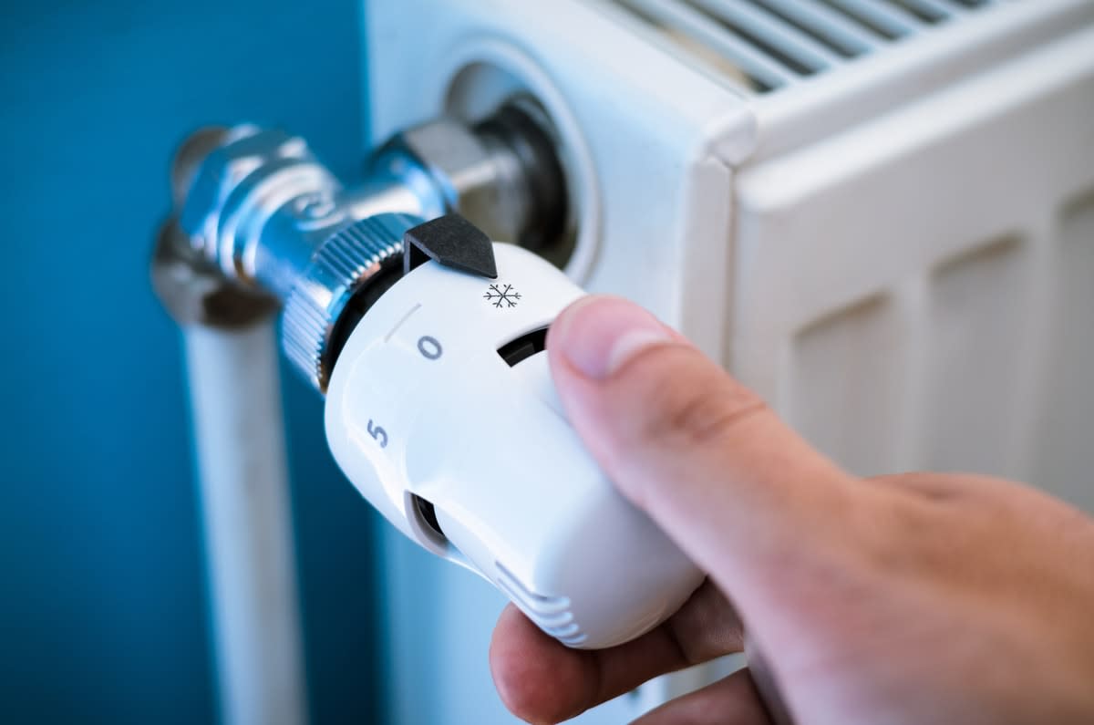 Close-up of a hand on the temperature control of a radiator heater