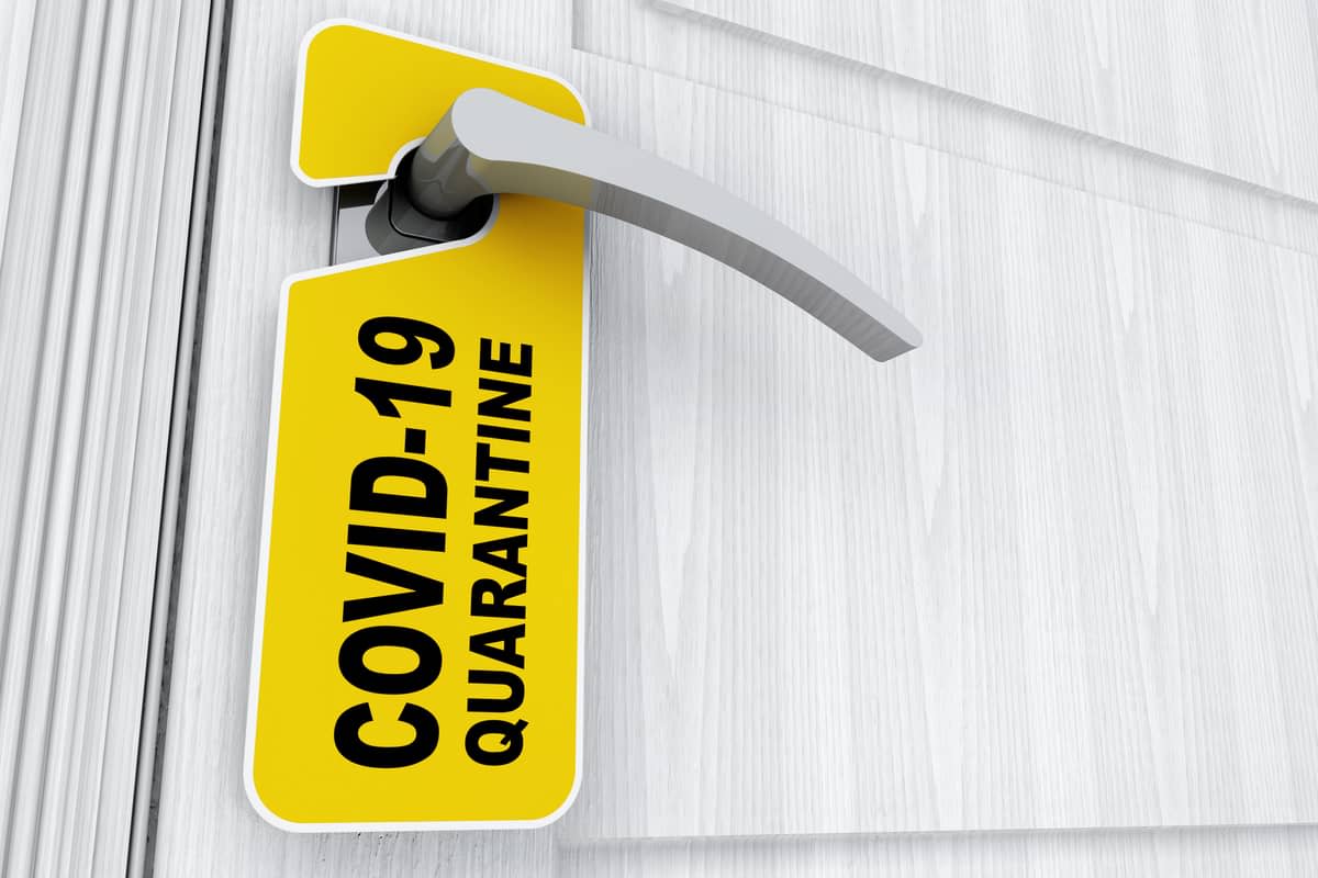 A door handle hung with a sign reading ‘COVID-19 quarantine‘