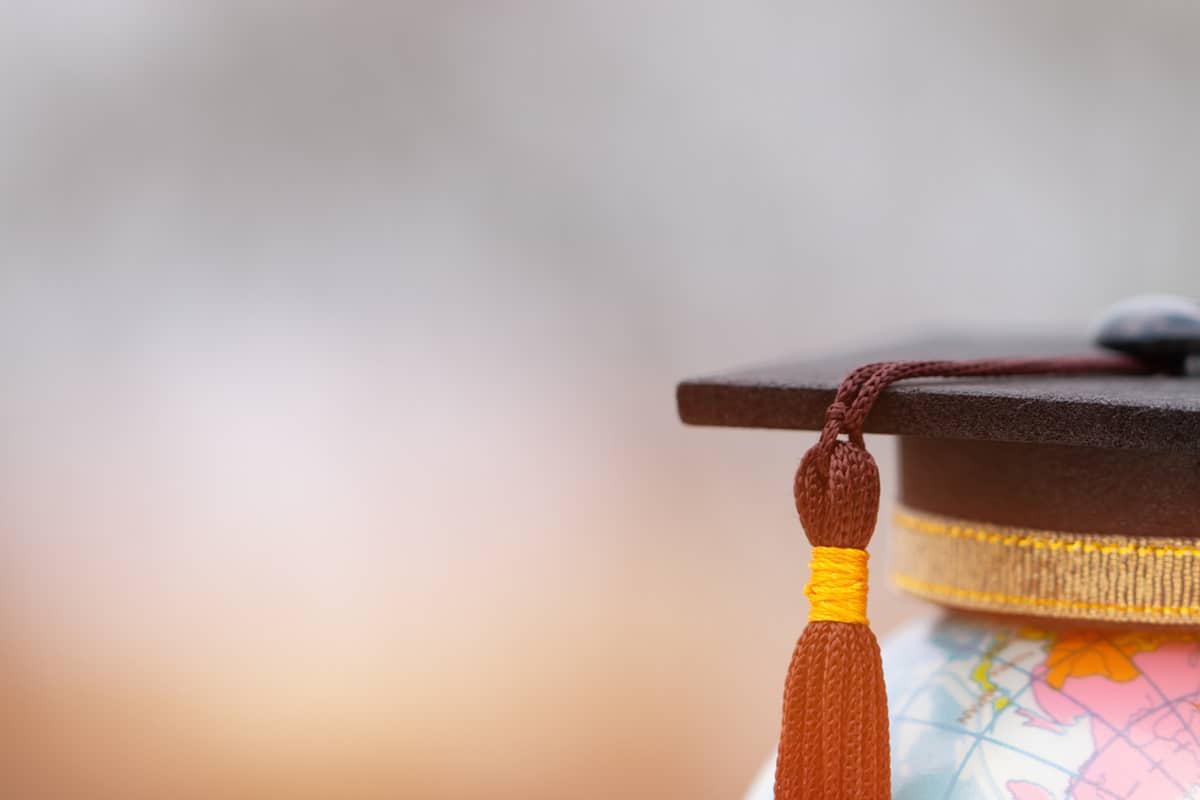 Close-up of a mortarboard hat sitting on a globe of the world