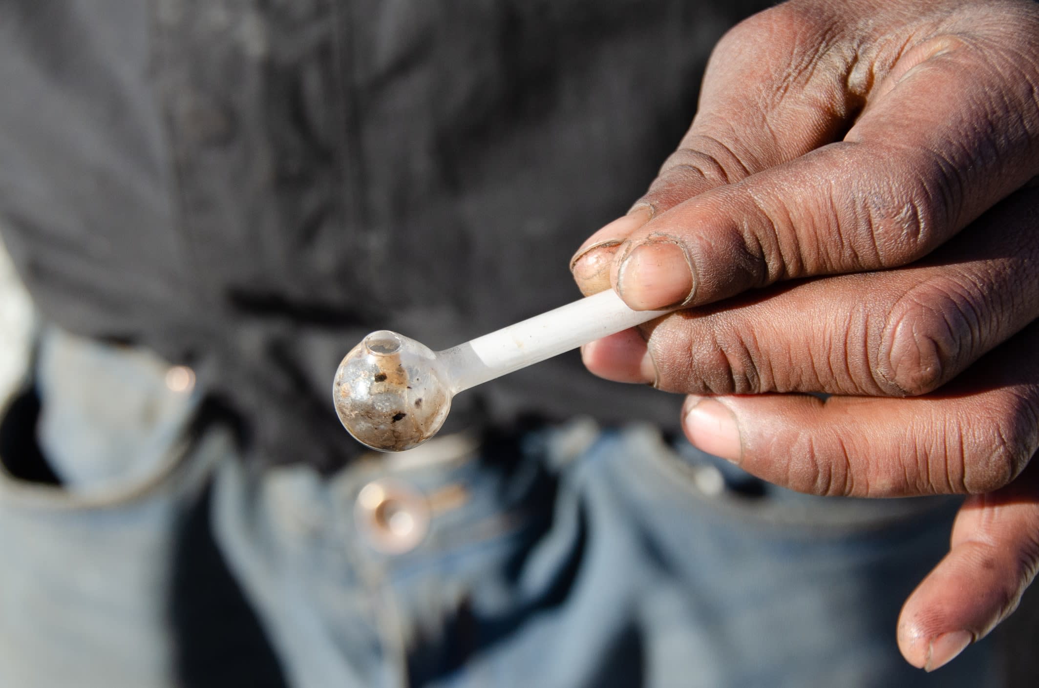 A hand holding a used amphetamine glass pipe