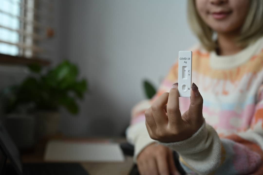 A young girl holds up a Rapid Antigen test result