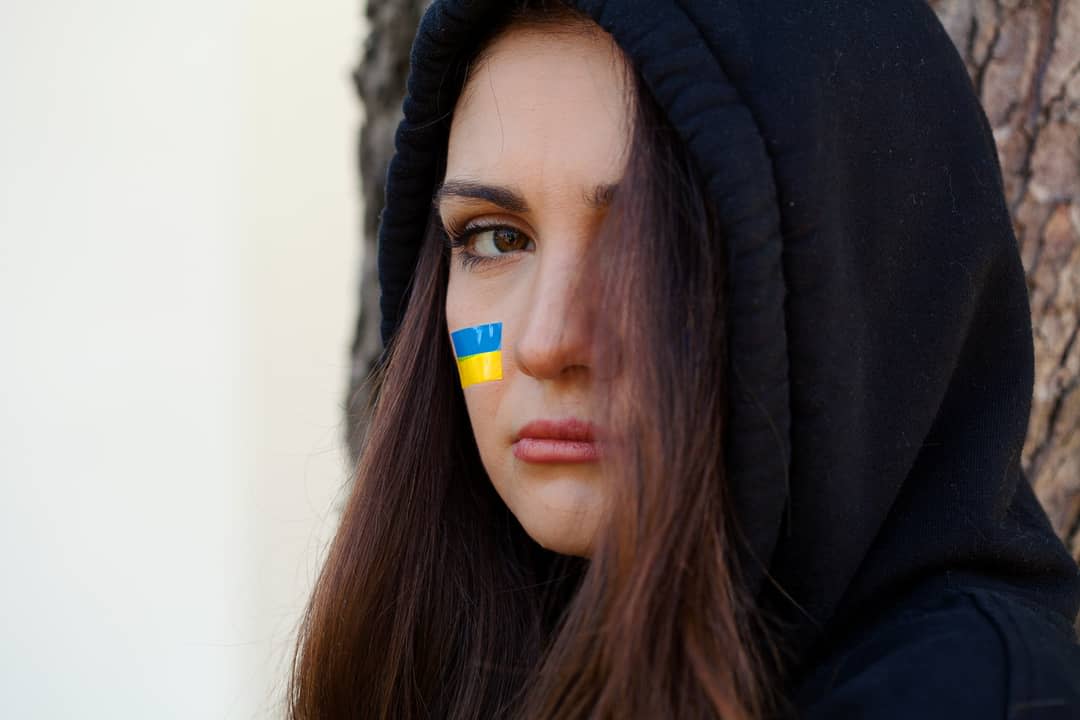 A young woman with a Ukraine flag painted on her face.