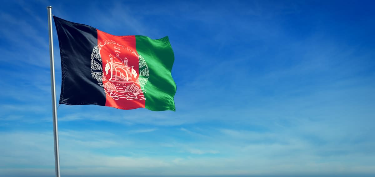 The Afghanistan flag flying with a blue sky backdrop