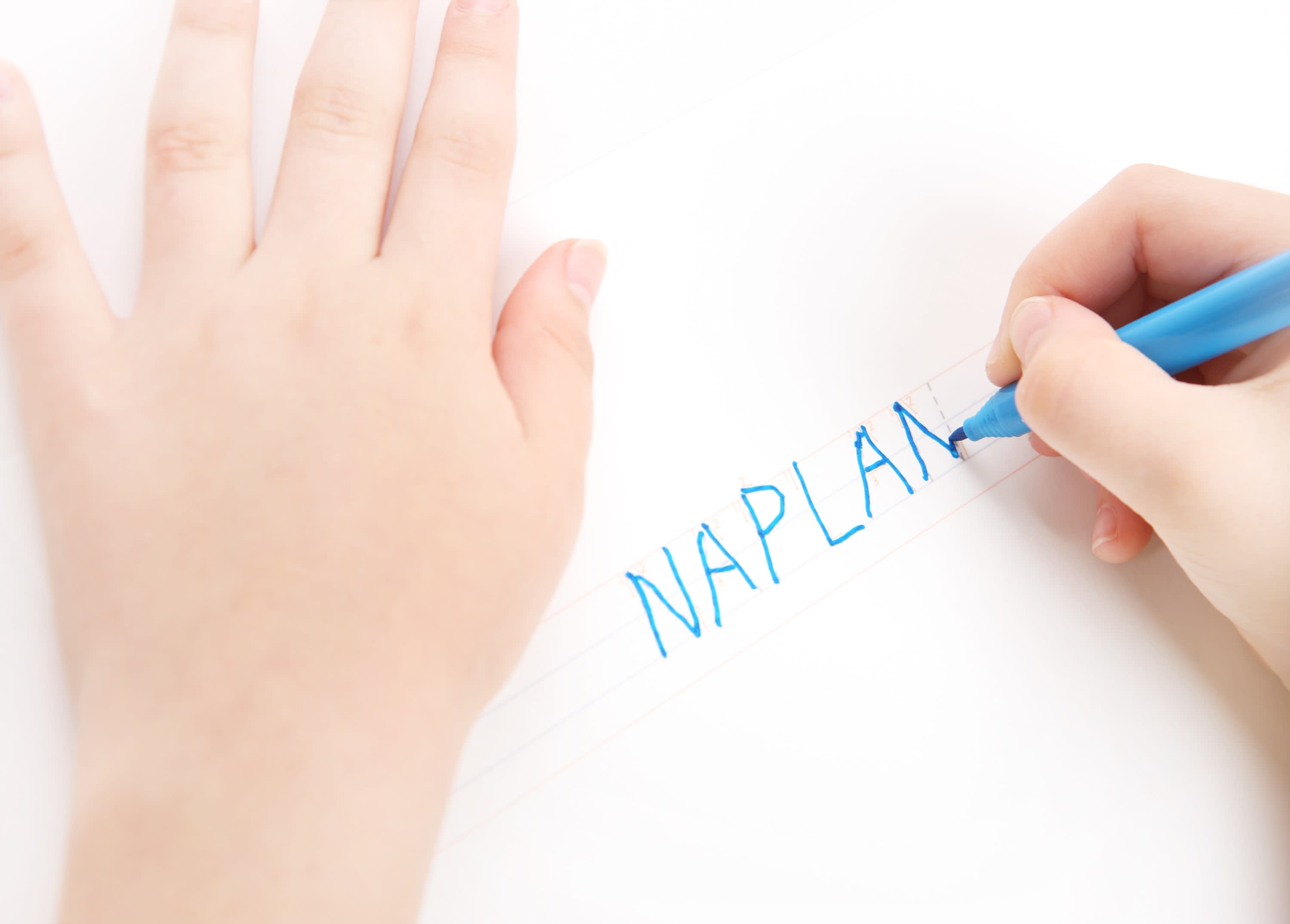 A young student writing the word 'NAPLAN'