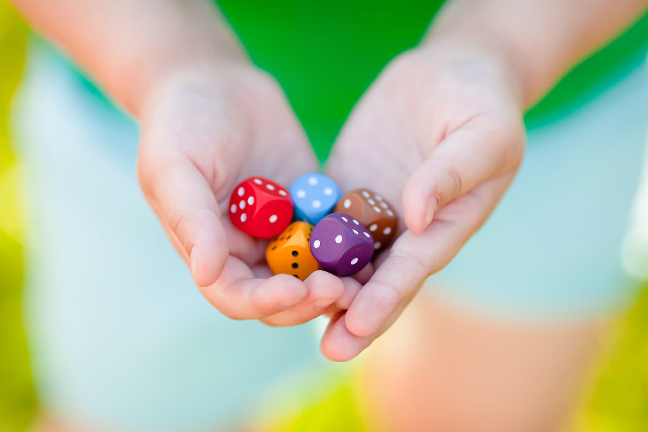 Mixed-coloured dice in child's hands.