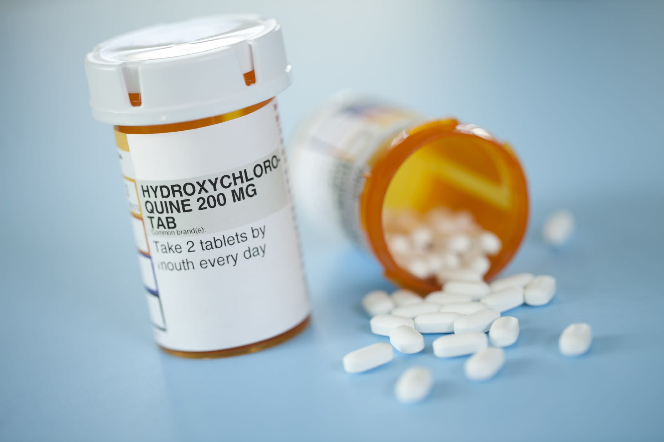 Pill bottles of hydroxychloroquine, one spilling pills onto a surface