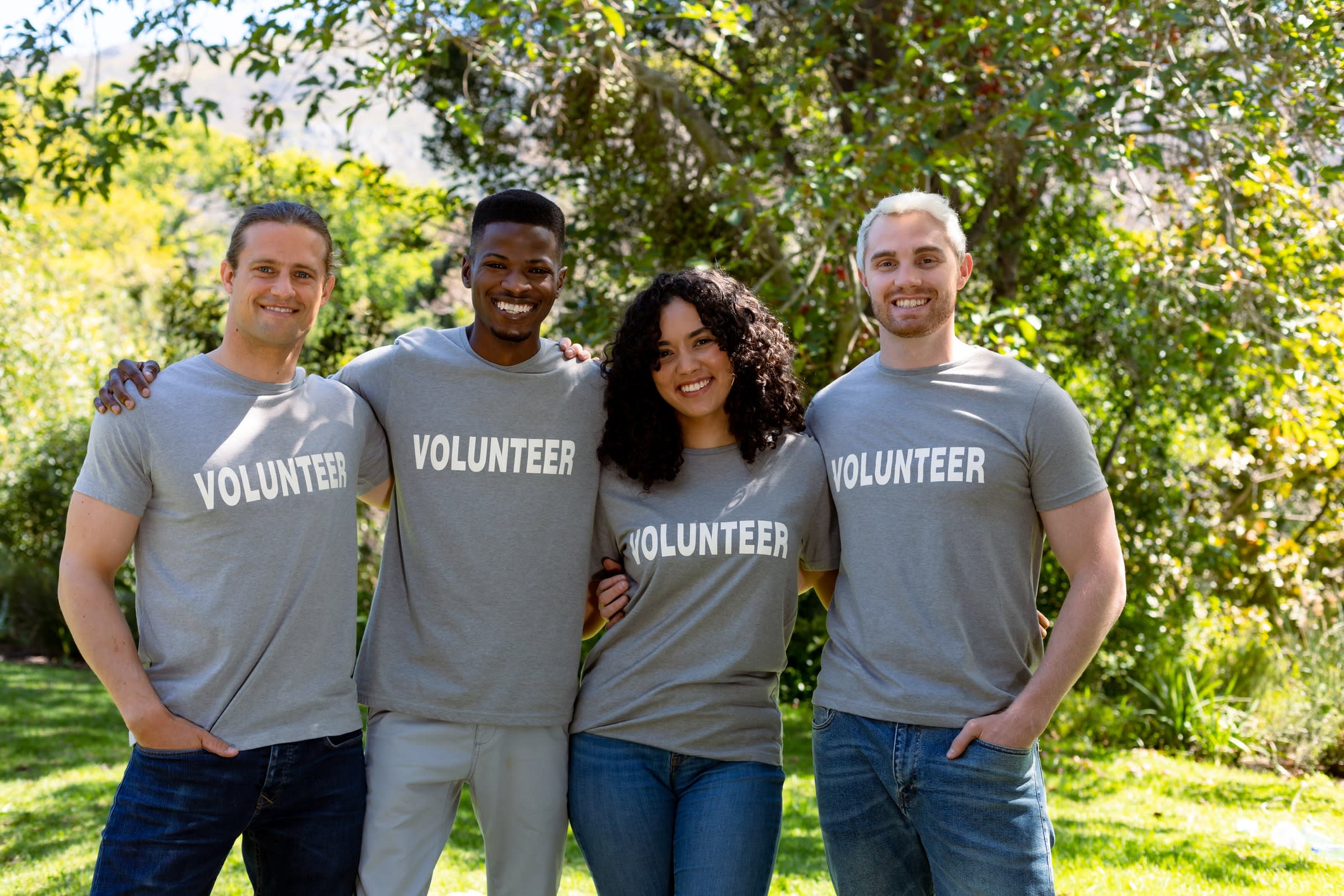 A group of smiling men and women volunteers in matching grey t-shirts