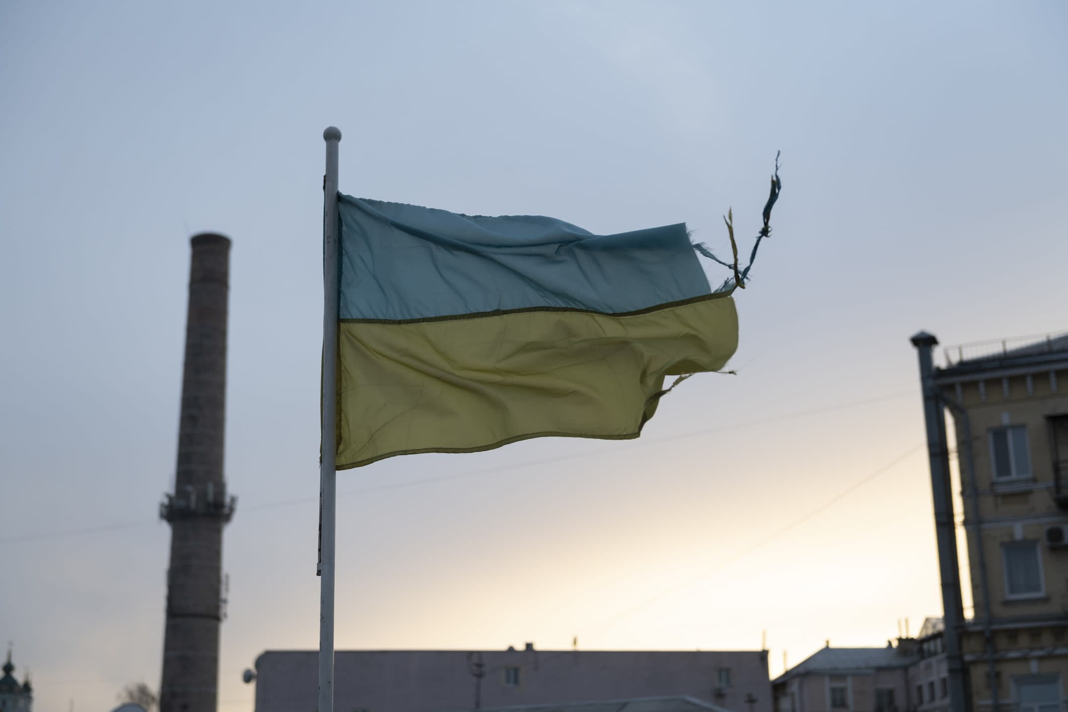 A tattered Ukrainian flag flying in an industrial area