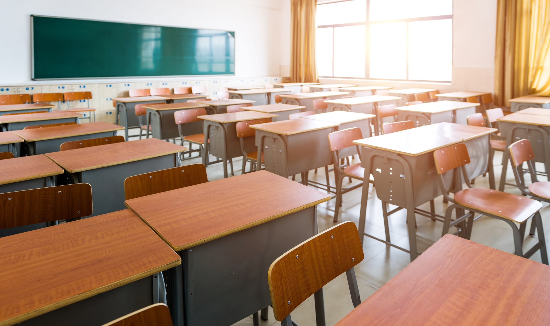 An empty classroom with rows of desks.