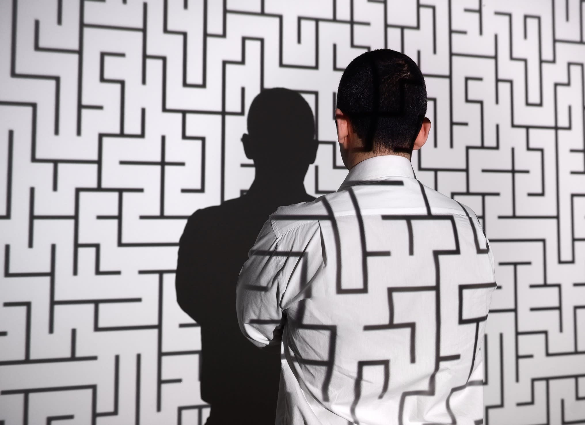 A businessman stands in front of a maze