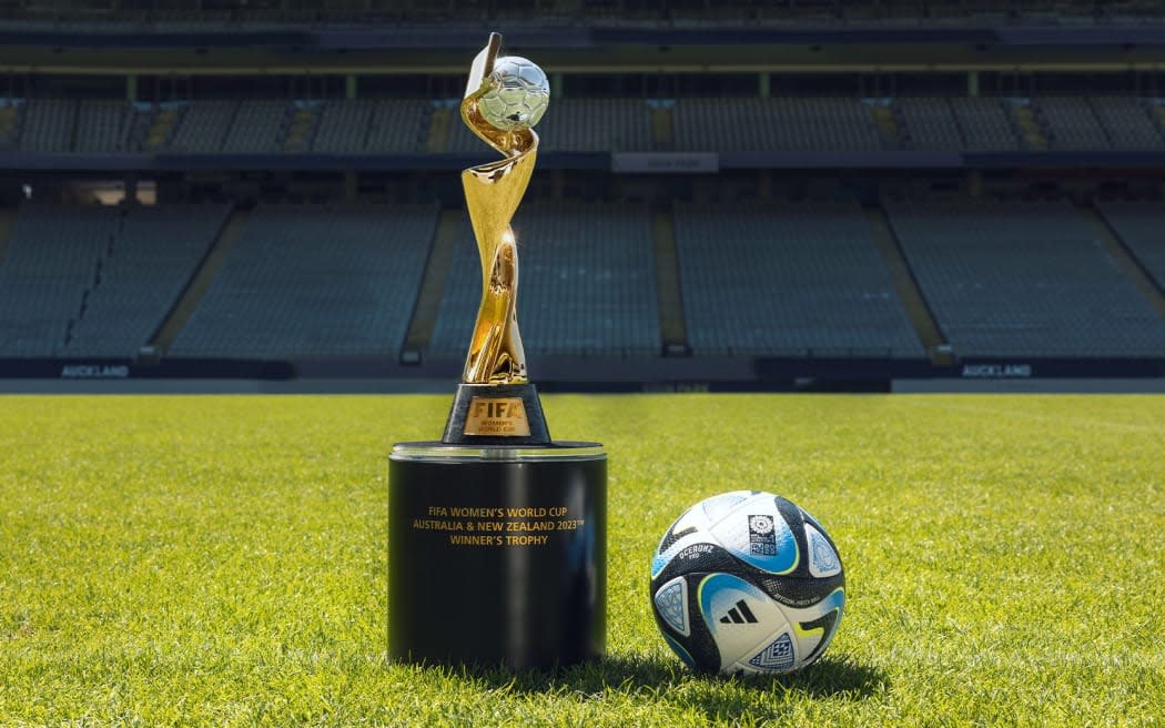 The Women's World Cup trophy and a football on a pitch in an empty stadium