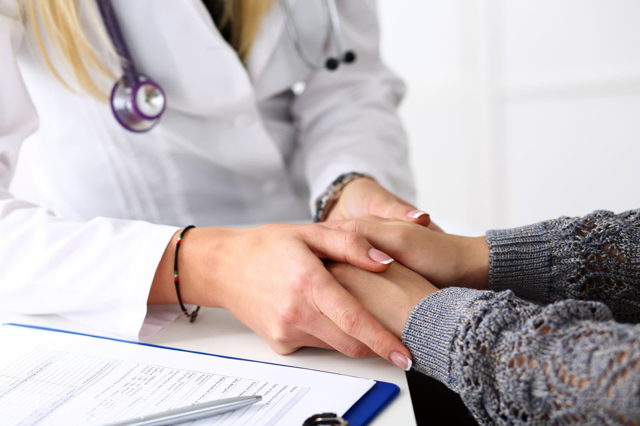 A female doctor holding a patient's hand in an office