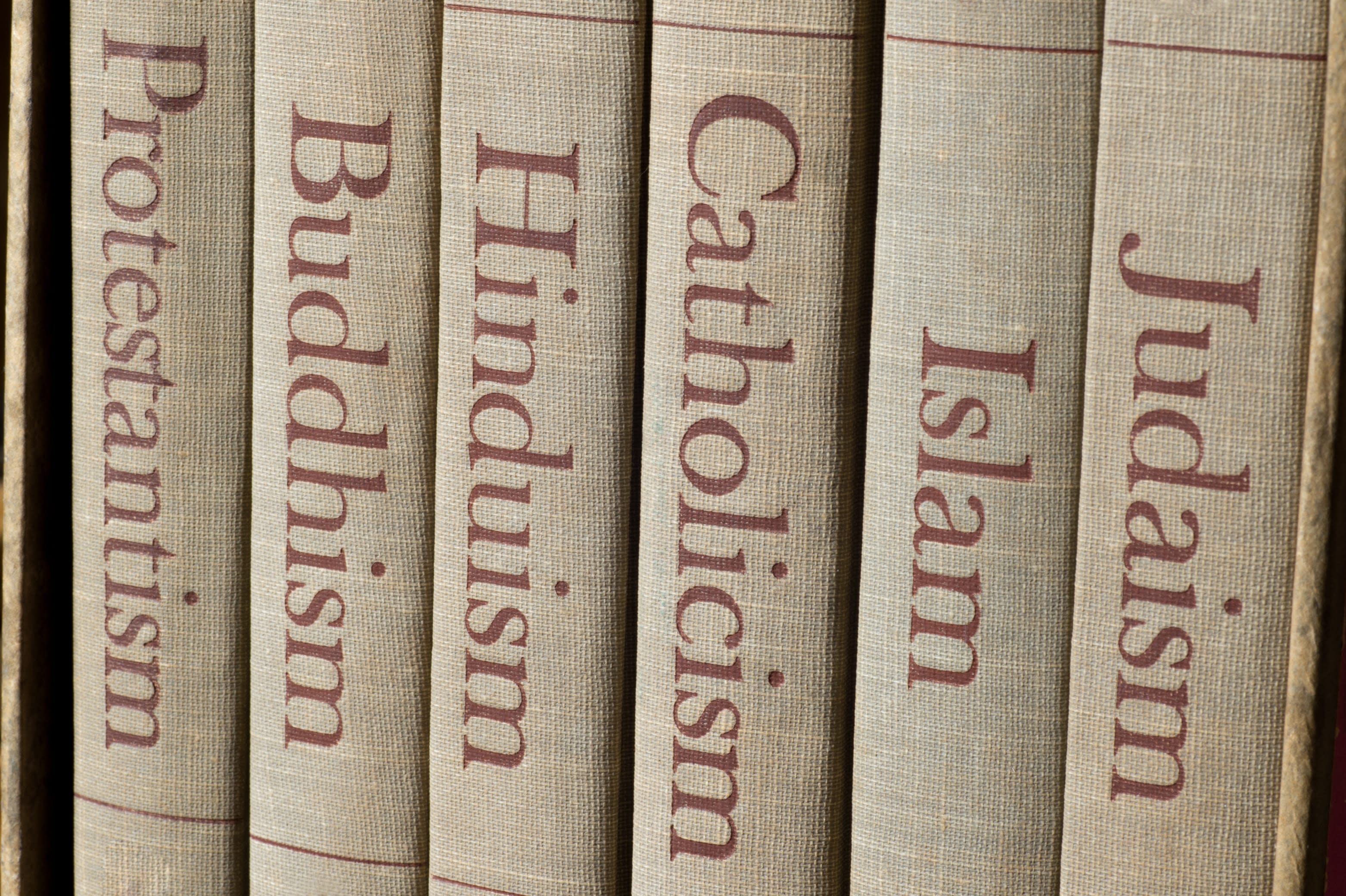 Book spines listing major world religions - Judaism, Islam, Catholicism, Hinduism, Buddhism and Protestantism