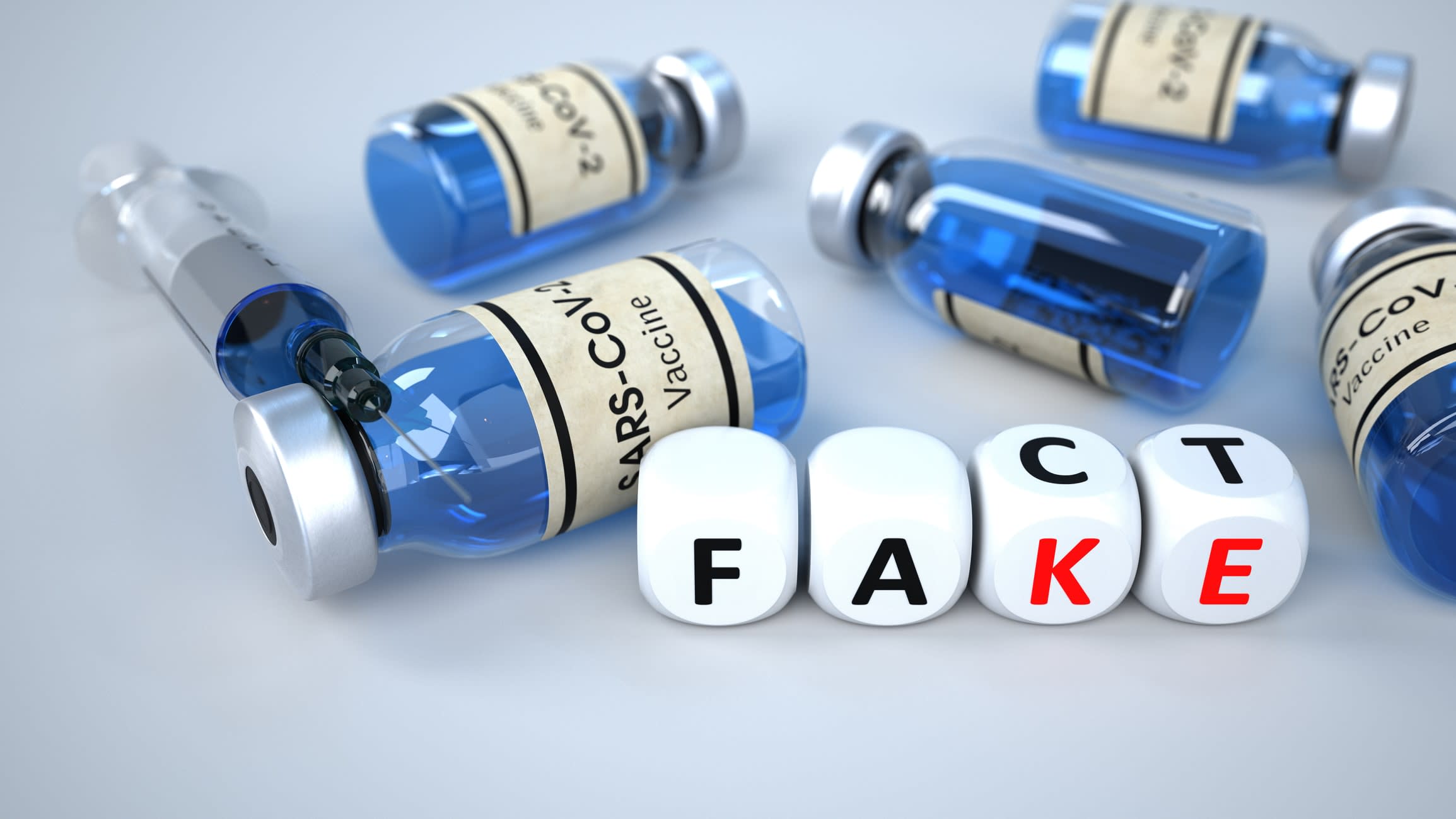 Vial of COVID vaccine with syringes, with dice spelling out 'FACT' AND 'FAKE' in the foreground