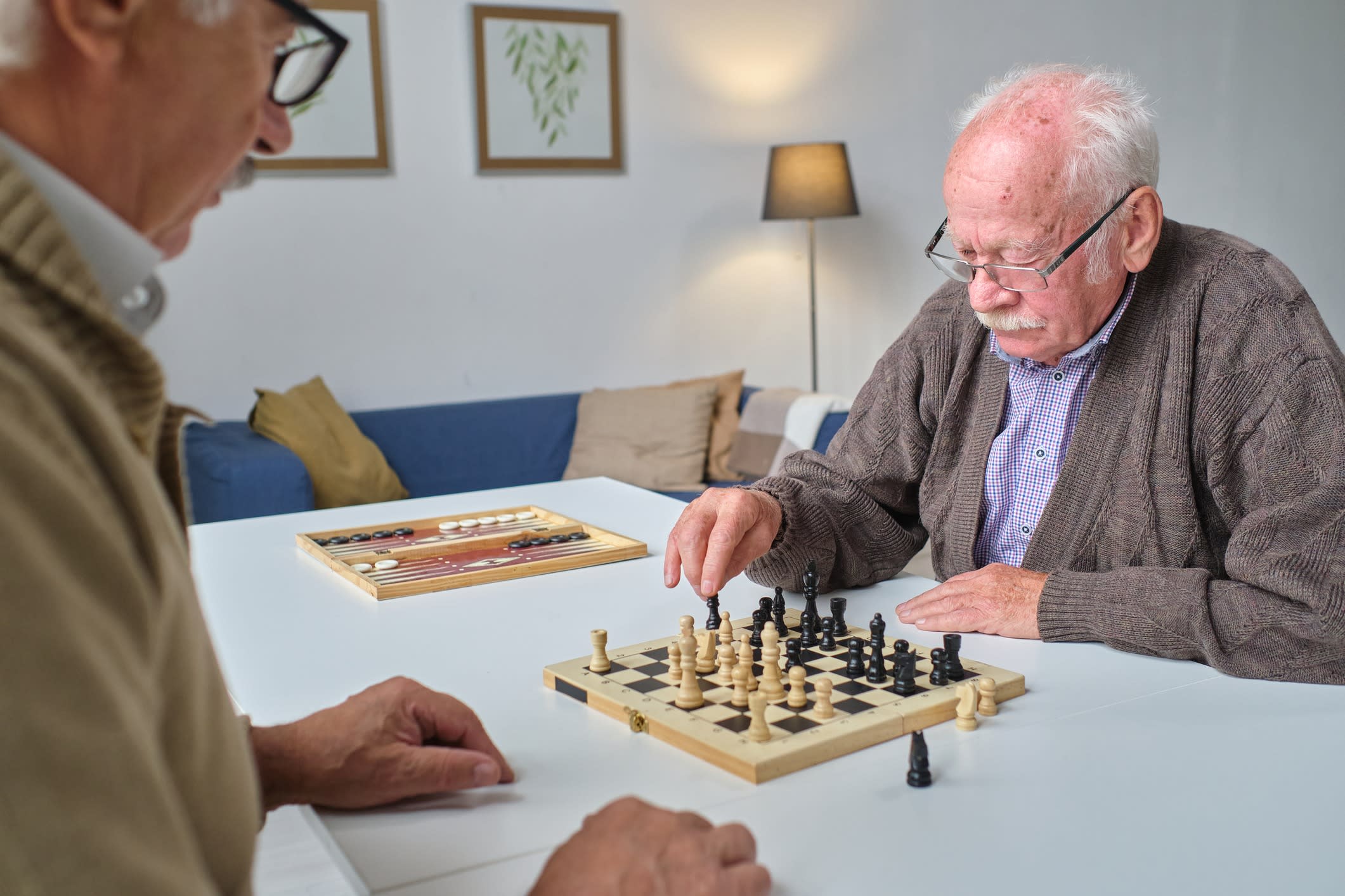 Two elderly men play a game of chess.