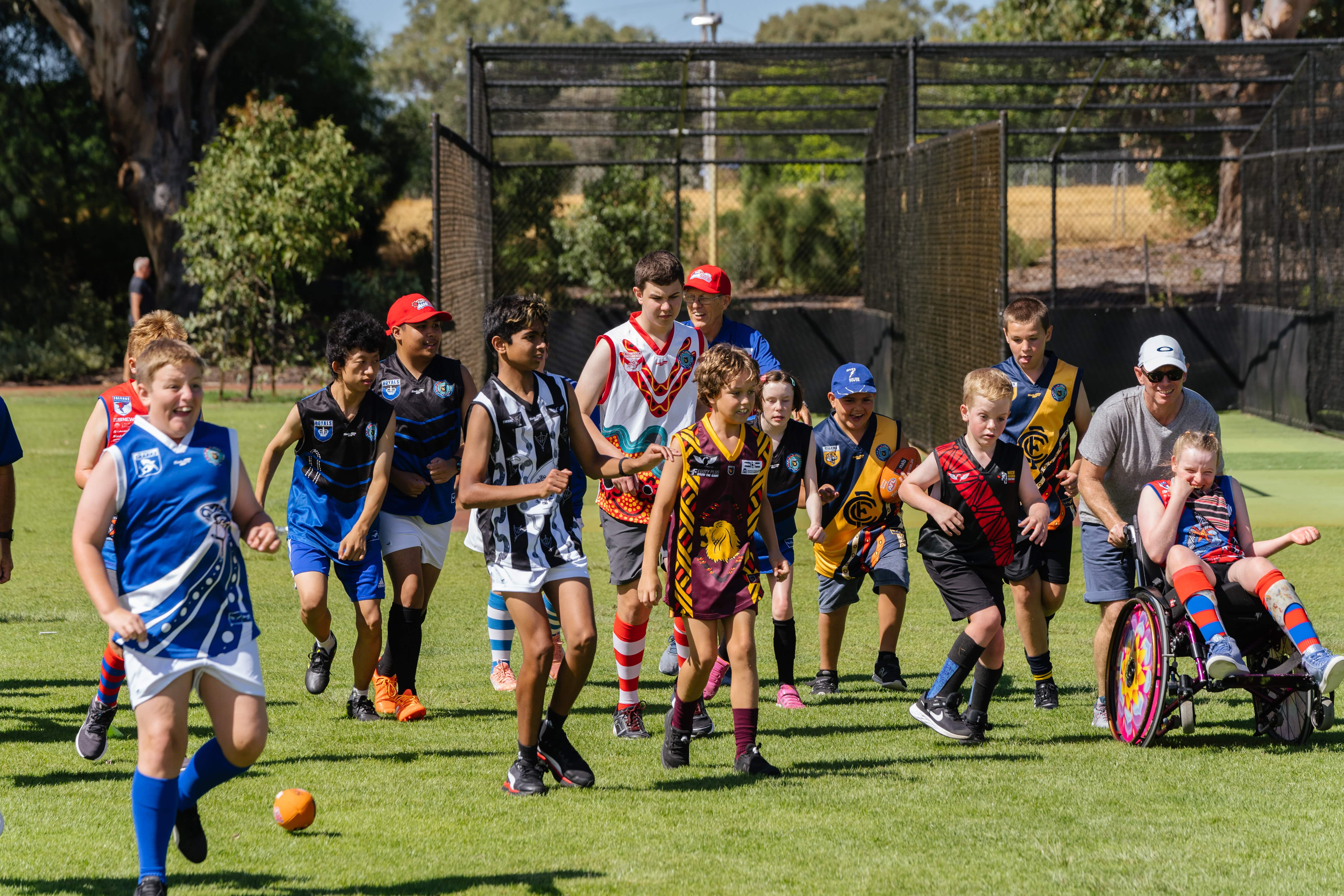 A group of kids on a field in various colourful football uniforms